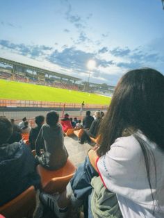 some people are sitting in the bleachers at a baseball game and watching something