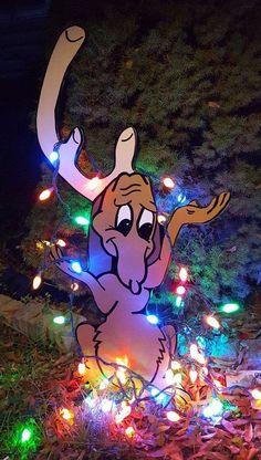 a light - up moose is sitting in the grass with its lights on it's back legs