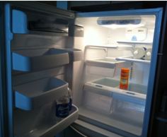 an open refrigerator with the door ajar and water in it's bottom drawer