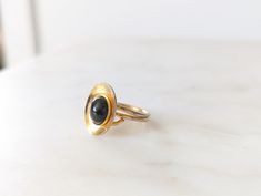 A stunning gold tone ring with large black stone, with aged patina on the band, that would make the perfect jewellery gift for you or a special someone. Colour: Gold, Black Materials: Metal Ring Size:  Size: D2cm  approx Info: In good vintage condition Check out our Instagram page, give us a follow and a ❤️, https://www.instagram.com/curiofoundation/ All net profits from this sale go directly to the Curio Foundation, your support helps us do vital work, so lives can be supported and changed. If Black Brass Rings For Gift, Elegant Brass Rings With Cabochon, Vintage Black Hand Forged Jewelry, Vintage Gold Rings With Black Enamel, Hand Forged Black Rings, Hand Forged Black Rings For Anniversary, Page Instagram, Jewellery Gift, Instagram Page