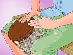 a person sitting on a chair with a drum in their lap and hands touching it