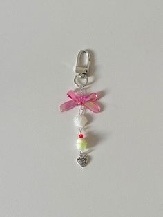 a key chain with charms attached to it on a white surface and a pink ribbon