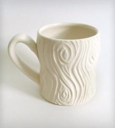 a white ceramic mug with wavy designs on the outside and inside, sitting on a white surface