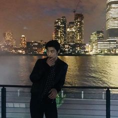 a man standing on top of a bridge next to the ocean with a city in the background