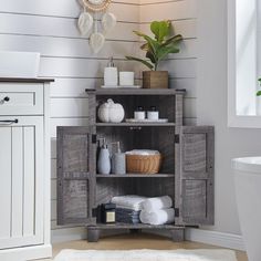 a bathroom with white walls and wooden shelves in the corner, along with a rug on the floor