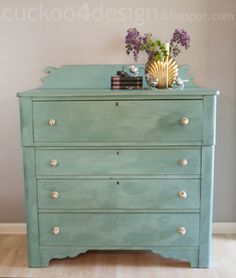 a green dresser with flowers and books on top