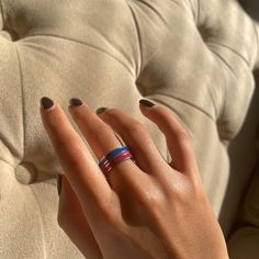 a woman's hand with two rings on it, sitting on a couch in front of a pillow