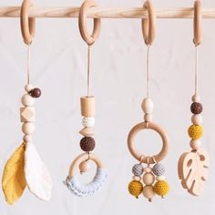 an assortment of wooden toys hanging from a clothes line with leaves and beads on them