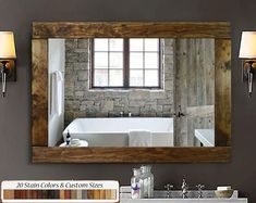 a bathroom mirror that is hanging on the wall above a sink and bathtub in front of a brick wall