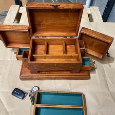 an open wooden box sitting on top of a table next to other boxes and keys