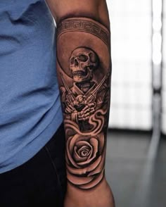 a man's arm with a skull and rose tattoo on the left side of his arm