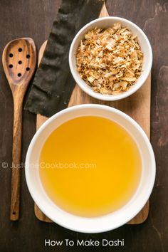 two bowls filled with food on top of a wooden cutting board next to a spoon