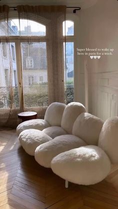 a large white couch sitting on top of a hard wood floor next to a window