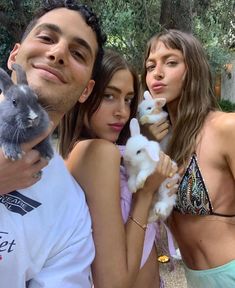 three people posing for a photo with two rabbits