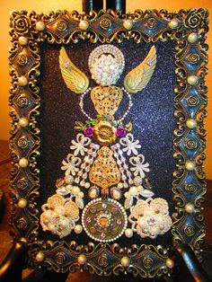 an ornate black and gold frame with pearls, jewels and angel wings on it's sides