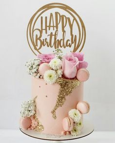 a pink and gold birthday cake with flowers on top