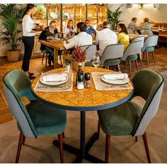 people sitting at tables in a restaurant with green chairs and yellow tablecloths on them