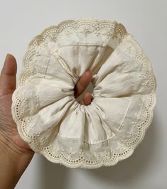 a hand holding a white doily in the shape of a flower