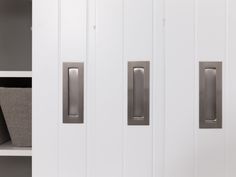 two white doors with metal handles in front of a book shelf and storage bins