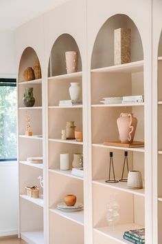 the shelves are filled with vases, books and other decorative items in varying shapes