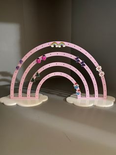 a pink and white shelf with three rainbows on it, sitting in front of a gray wall