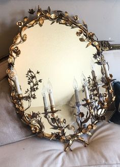 a mirror sitting on top of a bed next to two candles