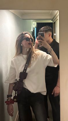 a man and woman taking a selfie in the mirror