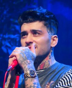 a man with tattoos on his arm holding a microphone