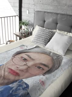 a bed with an image of a woman wearing glasses on the comforter and pillows