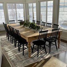 a dining room table surrounded by chairs in front of large windows with water outside the window