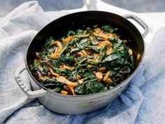 a pan filled with spinach and mushrooms on top of a blue towel