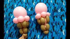 two pink and brown balloons sitting on top of a blue tablecloth covered floor next to a person's hand