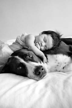 a black and white photo of a baby sleeping next to a dog