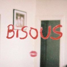 the word bisous written in red ink on a white wall next to an open door