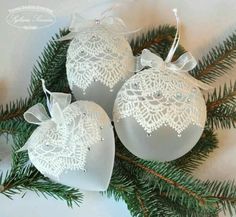 three white christmas ornaments with bows on them