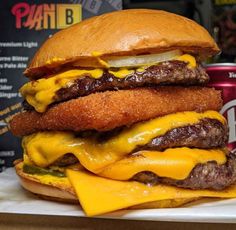 a cheeseburger with onion rings and pickles on the side next to a can of beer