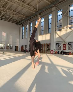 a man doing a handstand on his skateboard in an empty warehouse area