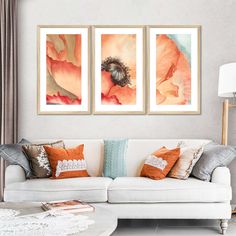 three paintings hang on the wall above a couch in a living room with white furniture