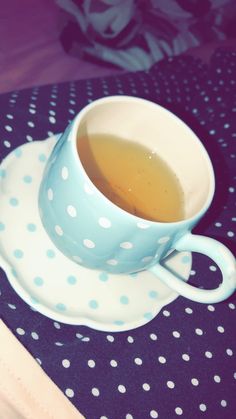 a cup of tea sitting on top of a polka dot saucer next to a spoon