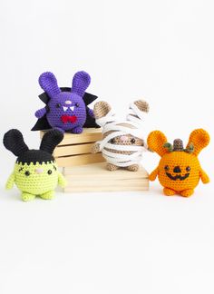 three crocheted stuffed animals sitting next to each other on a wooden crate with white background