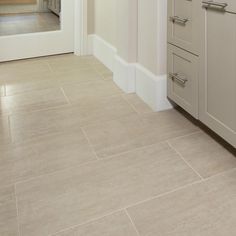 an empty kitchen with white cabinets and beige flooring