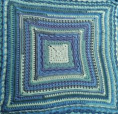 a blue crocheted blanket with a square in the center