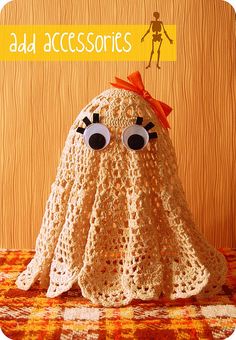 a crocheted stuffed animal with eyes on it's head and an orange bow around its neck