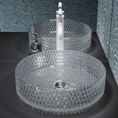 two clear glass bowls with toothbrushes in them on a black countertop next to blue mosaic tiles