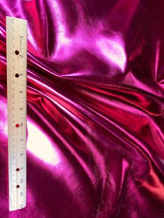 a ruler measuring the width of a shiny purple material that is very soft and smooth