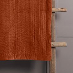 an orange blanket hanging on a wooden ladder