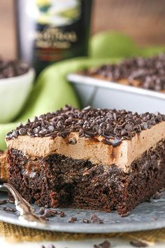 a piece of chocolate cake on a plate with a bite taken out of it and the rest of the cake in the background