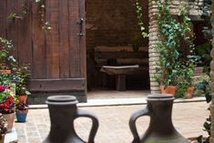 two vases sitting in front of a wooden door with potted plants on the outside