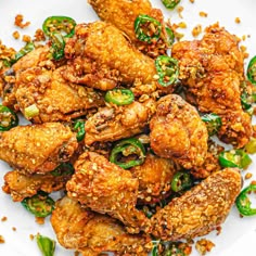 fried chicken with sesame seeds and green peppers on a white plate, ready to be eaten