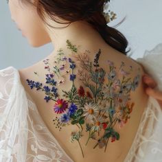 the back of a woman's neck is adorned with flowers and leaves on it